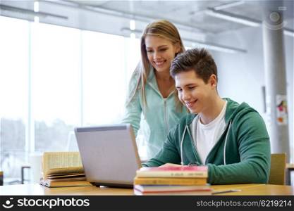 education, people, technology and learning concept - happy high school students with laptop computer in classroom or library