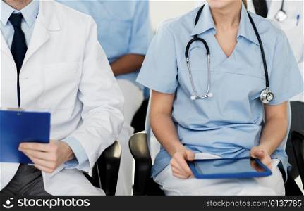 education, profession, people and medicine concept - close up of happy doctors with tablet pc computer and clipboard at seminar or hospital