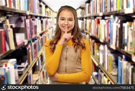 education, reading and silence concept - young teenage student girl making hush gesture over library background. student girl making hush gesture at library