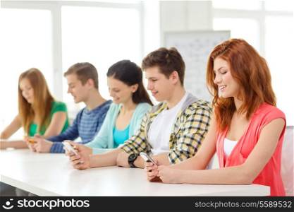 education, relationships and technology concept - group of smiling students with smartphones at school