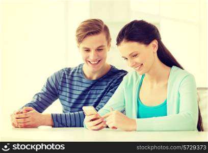 education, relationships and technology concept - two smiling students with smartphone at school