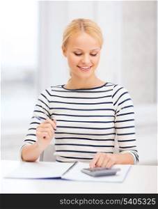 education, school and business concept - smiling woman with notebook and calculator studying in college