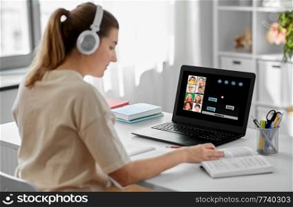 education, school and distant learning concept - female teacher in headphones with laptop computer and book having online class with little students at home. female teacher with laptop having online class