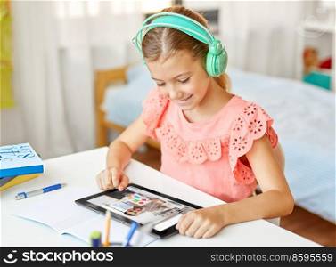 education, school and distant learning concept - happy student girl in headphones with tablet computer having online class at home. girl with tablet pc having online class at home