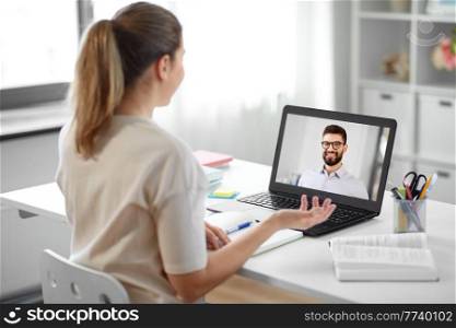 education, school and distant learning concept - student woman with laptop computer having video call with man or teacher at home. student woman with laptop has video call with man