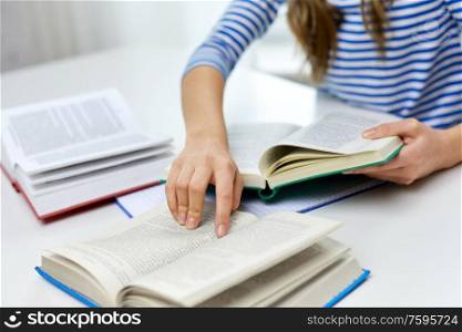 education, school and knowledge concept - close up of student girl with books learning at home. close up of student girl reading books at home
