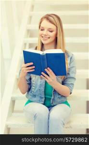 education, school and learning concept - smiling teenage girl reading book and sitting on staircase