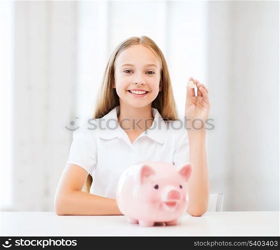 education, school and money saving concept - child putting coins into piggy bank
