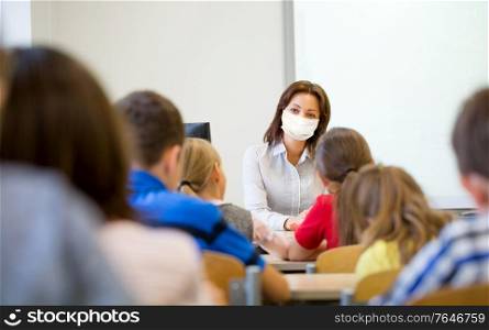 education, school and pandemic concept - teacher wearing face protective medical mask for protection from virus disease teaching group of students in classroom. teacher in mask with group of children at school