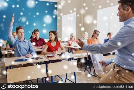 education, school and people concept - group of happy students and teacher with papers or tests over snow. group of students and teacher with papers or tests
