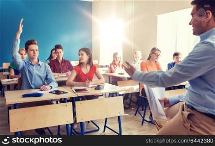 education, school and people concept - group of happy students and teacher with papers or tests. group of students and teacher with papers or tests