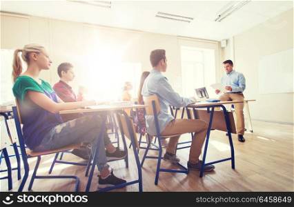 education, school and people concept - group of happy students and teacher with papers or tests. group of students and teacher with papers or tests