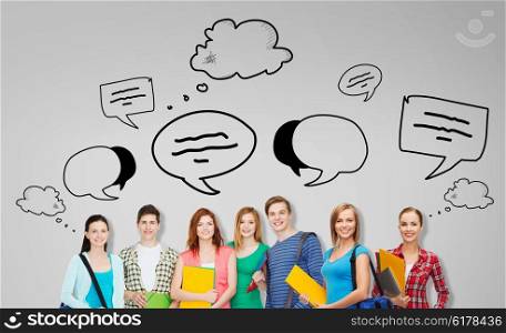 education, school and people concept - group of smiling teenage students with folders and school bags over gray background with text bubbles