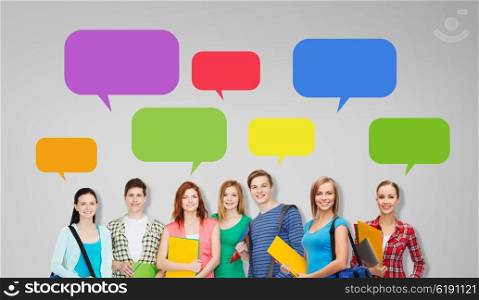 education, school and people concept - group of smiling teenage students with folders and school bags over gray background with empty text bubbles