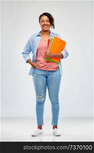 education, school and people concept - happy african american young student woman with notebooks over grey background. african american student woman with notebooks