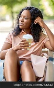 education, school and people concept - happy smiling african american student girl with takeaway coffee cup and backpack resting on bench in city. african woman with coffee and backpack in city