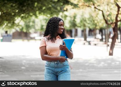 education, school and people concept - happy smiling african american student girl with notebooks in city. african student girl with notebooks in city
