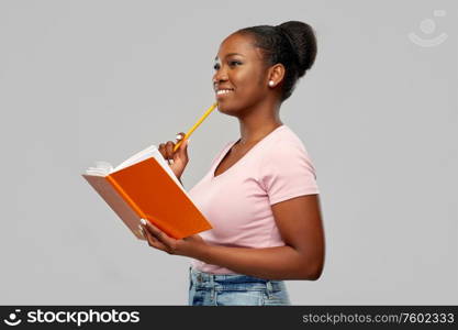 education, school and people concept - happy smiling african american woman with notebook and pencil over grey background. happy african american woman with notebook