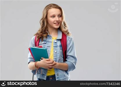 education, school and people concept - happy smiling teenage student girl with bag and books over grey background. happy smiling teenage student girl with school bag