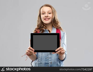 education, school and people concept - happy smiling teenage student girl with bag showing blank tablet computer screen over grey background. student girl with school bag and tablet computer