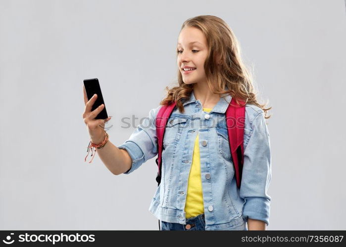 education, school and people concept - happy smiling teenage student girl with bag taking selfie by smartphone over grey background. teenage student girl taking selfie by smartphone