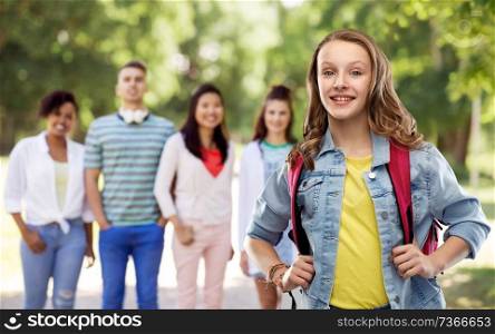 education, school and people concept - happy smiling teenage student girl with bag over group of friends in summer park background. happy smiling teenage student girl with school bag