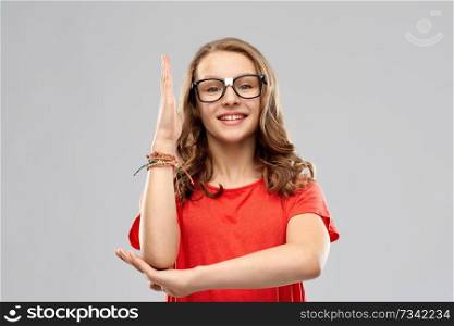 education, school and people concept - smiling teenage student girl in glasses and red t-shirt ready to answer over grey background. smiling student girl in glasses ready to answer