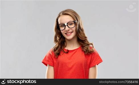 education, school and people concept - smiling teenage student girl in glasses and red t-shirt over grey background. smiling student girl in glasses and red t-shirt