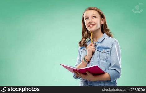 education, school and people concept - teenage student girl in denim jacket with diary or notebook and pencil thinking over green chalk board background. student girl with notebook over green background