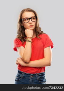education, school and people concept - teenage student girl in glasses and red t-shirt thinking over grey background. student girl in glasses thinking