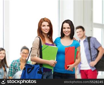 education, school and people concept - two smiling students with bag and folders standing
