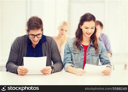 education, school and people concept - two teenagers holding test or exam with grade A