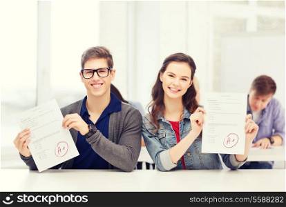 education, school and people concept - two teenagers holding test or exam with grade A