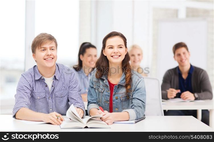 education, school and people concept - two teenagers with notebooks amd book listening to someone at school