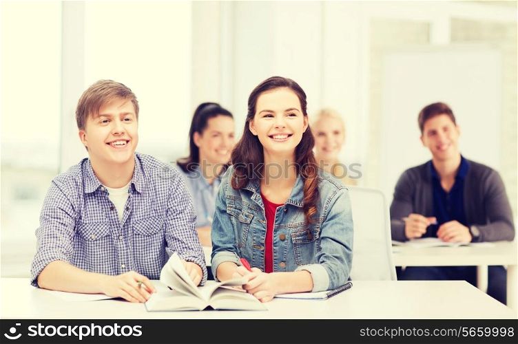 education, school and people concept - two teenagers with notebooks amd book listening to someone at school