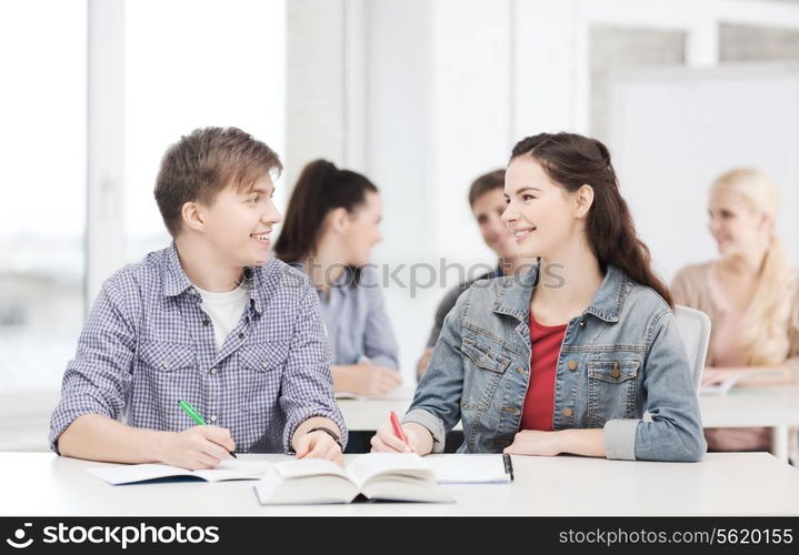 education, school and people concept - two teenagers with notebooks and book looking at each other at school