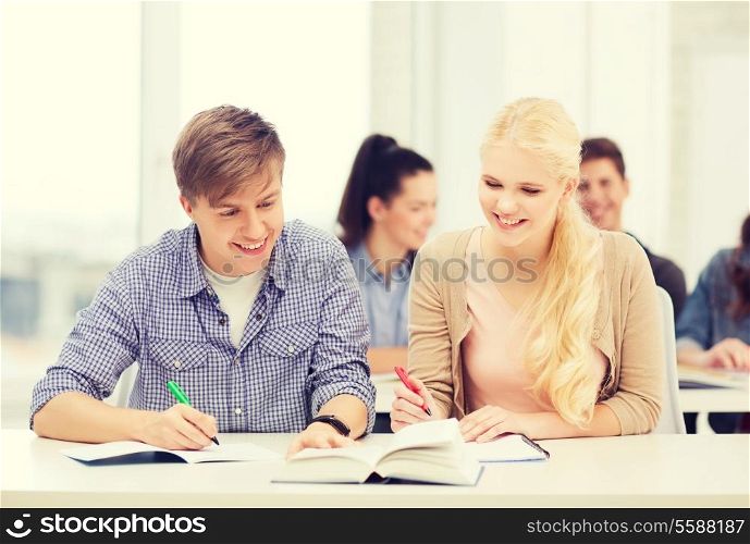 education, school and people concept - two teenagers with notebooks and book at school