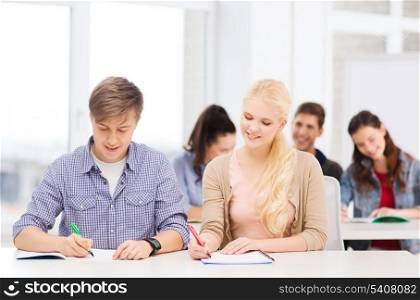 education, school and people concept - two teenagers with notebooks at school