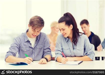 education, school and people concept - two teenagers with notebooks at school