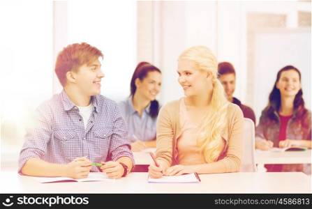 education, school and people concept - two teenagers with notebooks looking at each other at school