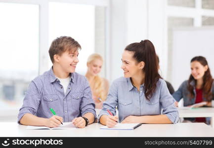 education, school and people concept - two teenagers with notebooks looking at each other at school