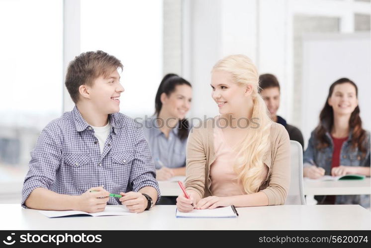 education, school and people concept - two teenagers with notebooks looking at each other at school