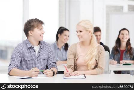 education, school and people concept - two teenagers with notebooks looking at each other at school