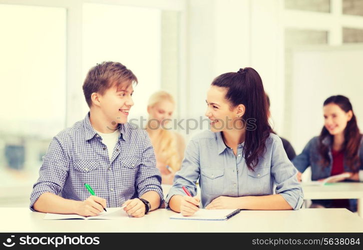 education, school and people concept - two teenagers with notebooks looking at each other at school