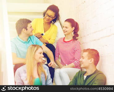 education, school and technology concept - smiling students with smartphone having discussion at school