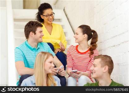 education, school and technology concept - smiling students with smartphone having discussion at school