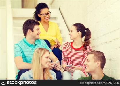education, school and technology concept - smiling students with smartphone having discussion at school