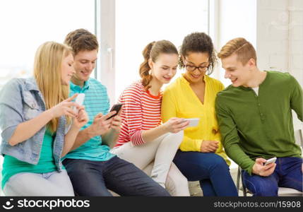 education, school and technology concept - smiling students with smartphone texting at school