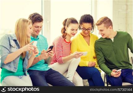 education, school and technology concept - smiling students with smartphone texting at school