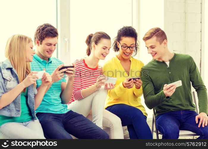 education, school and technology concept - smiling students with smartphone texting at school